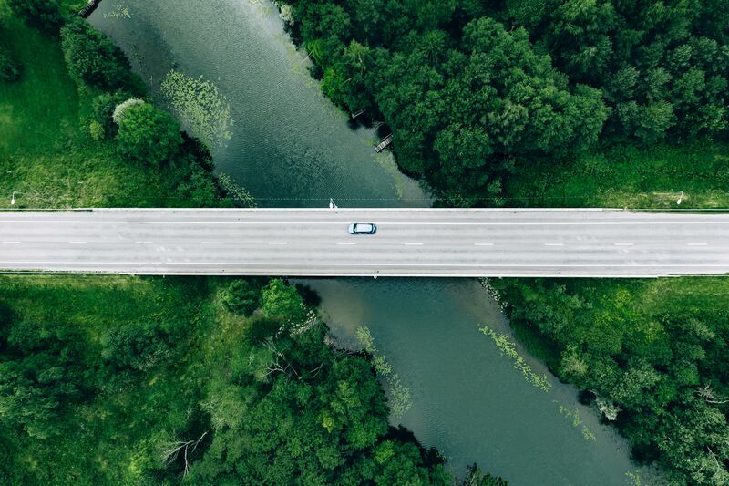 Aerial view of road with blue car over the river in Finland-Small