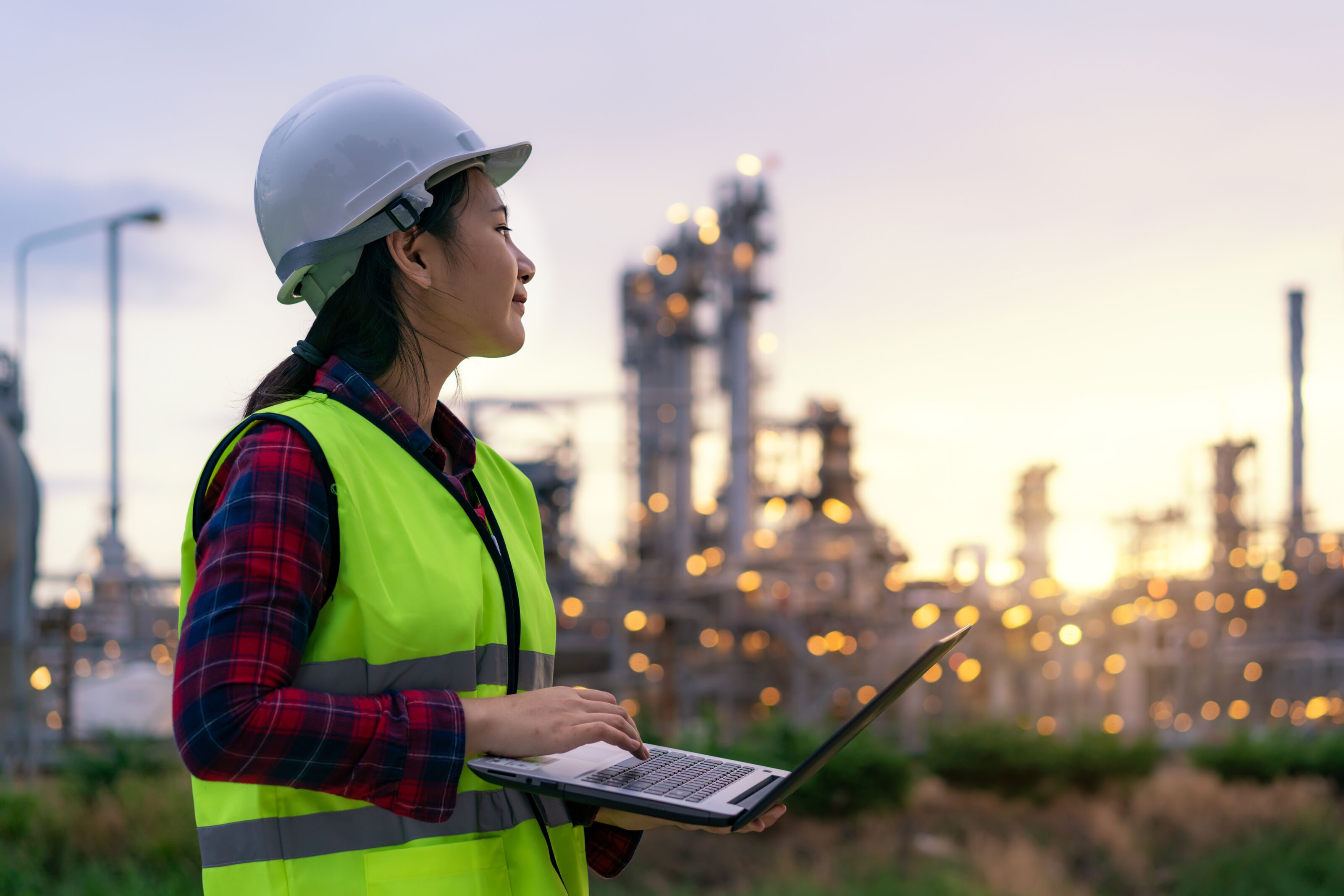 Woman-holding-a-a-tablet-wearing-an-helmet-and-looking-at-power-grids-in-the-background